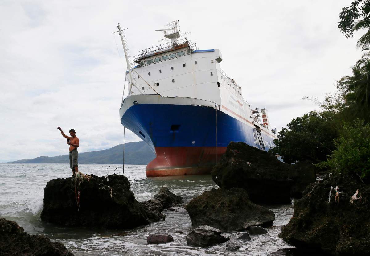 A resident takes a selfie of the passenger ferry Shuttle Roro 5 which rests by the shore after being swept by typhoon Nock-Ten a day after Christmas Monday, Dec. 26, 2016 at Mabini township, Batangas province south of Manila, Philippines. The powerful typhoon slammed into the eastern Philippines on Christmas Day, spoiling the biggest holiday in Asia’s largest Catholic nation but weakened slightly on Monday as it roared toward a congested region near the country’s capital, officials said.
