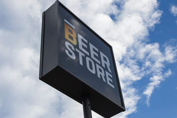 The sign for the Beer Store in front of clouds and blue sky.