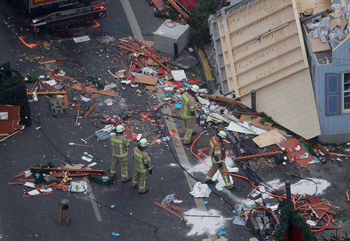 Firefighters look at the debris after the trailer has been towed away from the crime scene in Berlin, Germany, Tuesday, Dec. 20, 2016, the day after a truck plowed into a crowded Christmas market, killing several people.