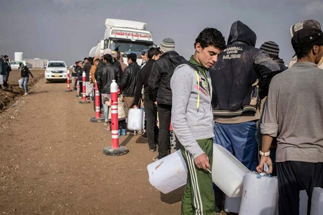 Men wait in line for fuel distributions at Sewdinan Camp for the displaced near Khazer, Iraq on Wednesday, Dec. 21, 2016. Human Rights Watch said Wednesday that Islamic State fighters are deliberately targeting civilians who refuse to join them as they retreat ahead of the advancing Iraqi forces. In a statement, it said at least 19 civilians were killed and dozens wounded in the period from the third week of November into the first week of December. (AP Photo/Cengiz Yar).