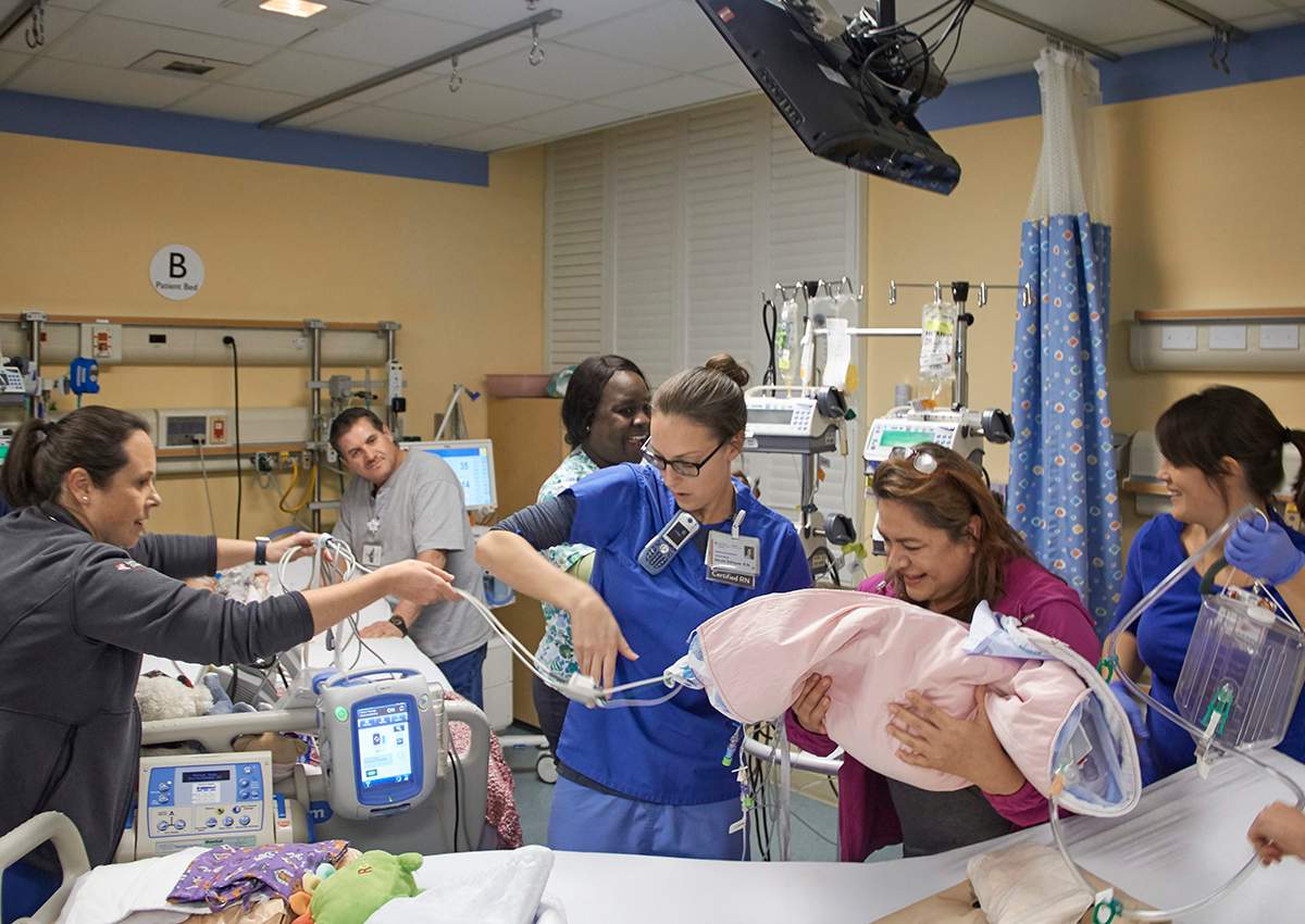 In this Monday, Dec. 12, 2016, photo provided by the Lucile Packard Children’s Hospital Stanford, Pediatric Intensive Care Unit members of the girls’ care team position Erika’s bed so that the twins’ mother, Aida Sandoval, second from right, could pick up her daughter, Erika, from her bed and place her next to her sister Eva, partially seen at left with her father, Arturo Sandoval, in Palo Alto, Calif.
