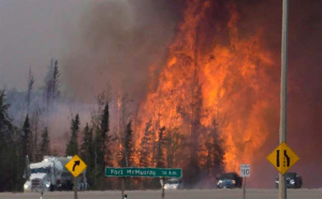 Heat waves are seen as cars and trucks try and get past a wild fire 16km south of Fort McMurray on highway 63 Friday, May 6, 2016. 