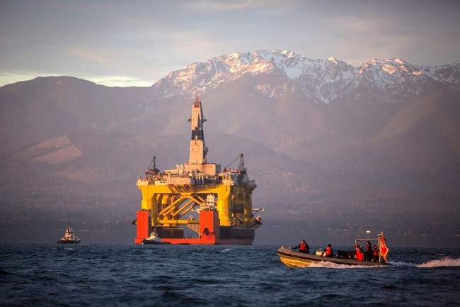 A boat crosses in front of the Transocean Polar Pioneer, a semi-submersible drilling unit as it arrives in Port Angeles, Wash., aboard a transport ship after traveling across the Pacific before its eventual Arctic destination in an April 17, 2015 file photo. 