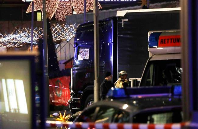 Police stand beside a damaged truck which ran into crowded Christmas market in Berliin Berlin, Germany, Monday, Dec. 19, 2016. (AP Photo/Michael Sohn).