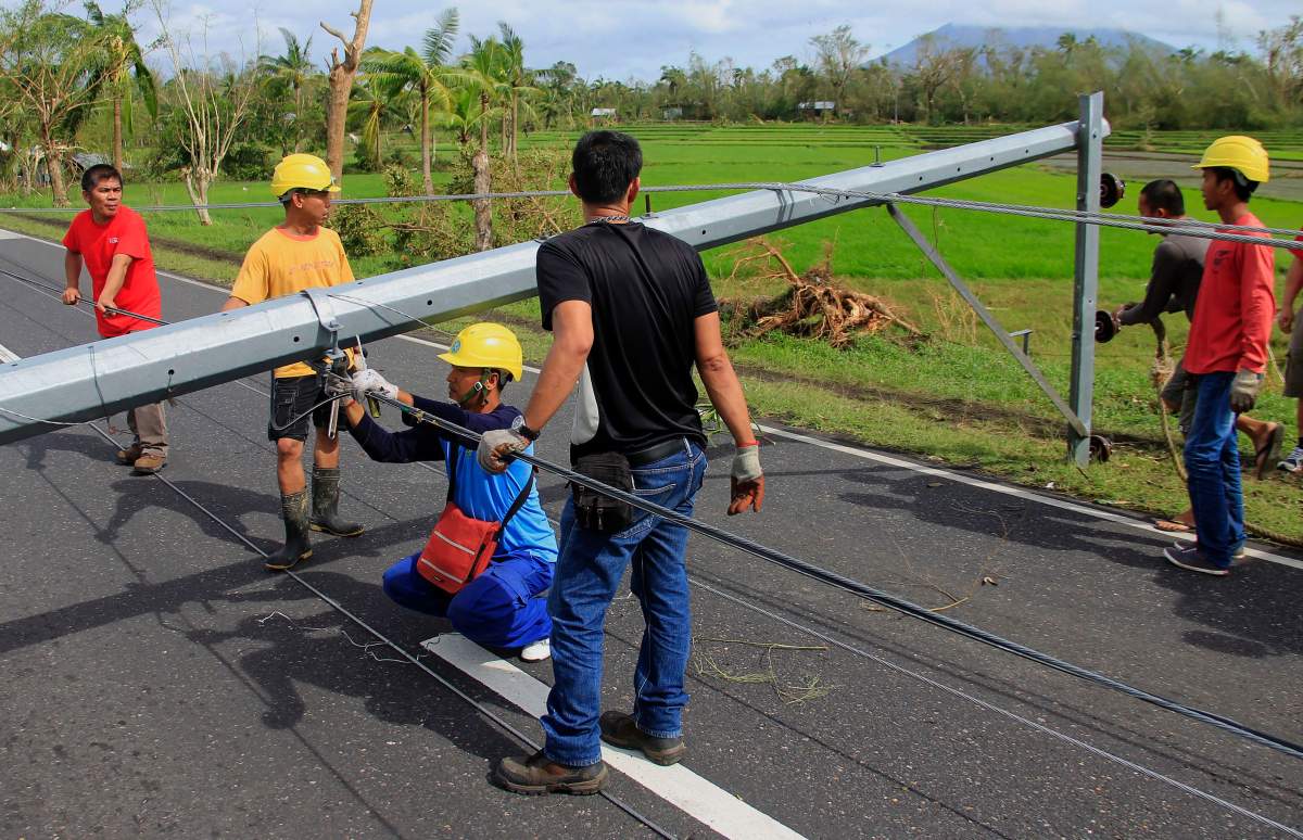Workers check downed electric posts on the national road after typhoon Nock-Ten made landfall in Nabua, Camarines Sur on December 26, 2016.Typhoon Nock-Ten, which made landfall on the eastern island province of Catanduanes on December 25, is forecast to move westward towards the country’s heartland, packing winds of 215 kilometres (134 miles) per hour. / AFP / Charism SAYAT (Photo credit should read
