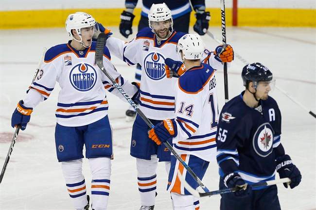 Edmonton Oilers' Ryan Nugent-Hopkins (93), Benoit Pouliot (67), and Jordan Eberle (14) celebrate Pouliot's goal against Mark Scheifele (55) and the Winnipeg Jets during third period NHL action in Winnipeg on Thursday, December 1, 2016.