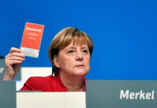 German Chancellor and Chairwomen of the CDU, Angela Merkel, holds an voting ticket during a party conference of the Christian Democratic Union (CDU) in Essen, Germany, Tuesday, Dec. 6, 2016. Chancellor Angela Merkel has won a new two-year term as leader of Germany's main conservative party after she won 89.5 percent of delegates' votes at a party congress. (AP Photo/Martin Meissner).