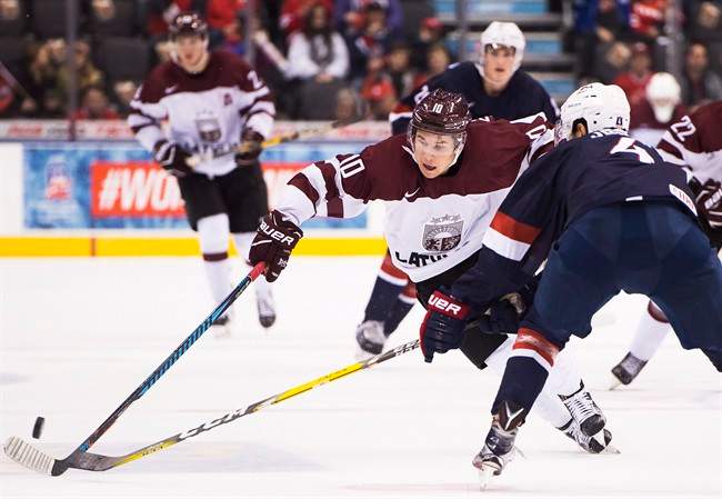 Latvia's Martins Dzierkals (10) drives past the United States' Caleb Jones (4) during third period IIHF World Junior Championships in Toronto on Monday, December 26, 2016. THE CANADIAN PRESS/Nathan Denette.