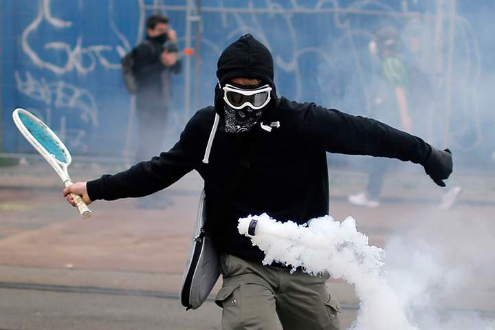 A protester uses a tennis racket to return a tear gas canister at a demonstration against the French government’s proposed labour law reforms in Nantes on June 2, 2016.