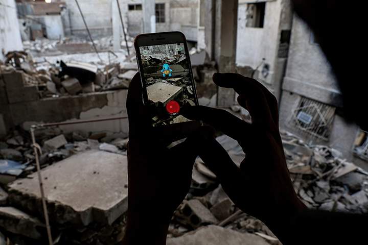 A Syrian gamer uses the Pokemon Go app on his mobile phone to catch a Pokemon amidst the rubble in the besieged rebel-controlled town of Douma, east of the capital Damascus on July 23, 2016.