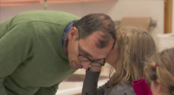 Kevin Finlayson bends down to listen as a student whispers into his ear.