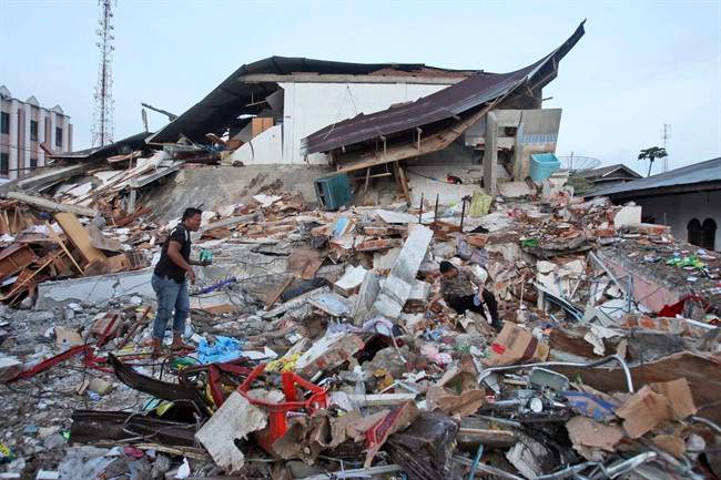 An Acehnese man and a police officer survey the damage after an earthquake in Ulhee Glee, Aceh province, Indonesia, Thursday, Dec. 8, 2016. Thousands of people in the Indonesian province of Aceh took refuge for the night in mosques and temporary shelters after a strong earthquake Wednesday killed a large number of people and destroyed dozens of buildings. (AP Photo/Binsar Bakkara).