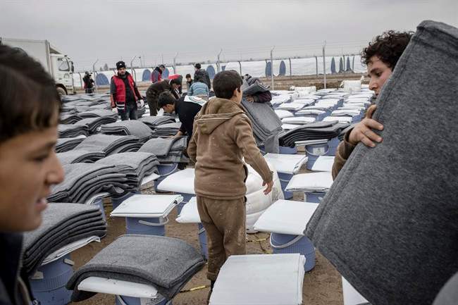 Iraqis displaced from Mosul receive aid distributions at near Qayara, Iraq on Wednesday, Dec. 28, 2016. (AP Photo/Cengiz Yar).