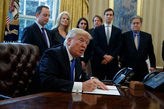 President Donald Trump signs an executive order on the Keystone XL pipeline, Tuesday, Jan. 24, 2017, in the Oval Office of the White House in Washington.