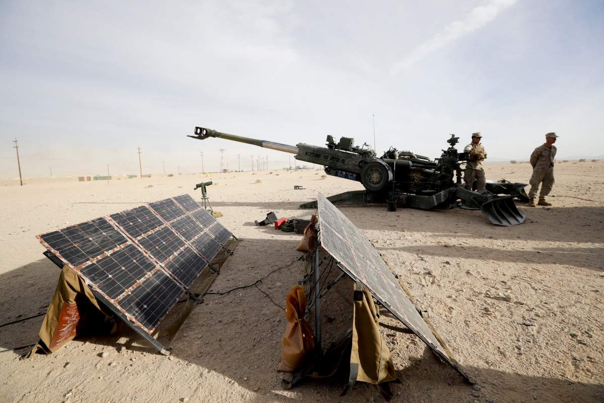 In this Dec. 7, 2016 photo, Marines stand near an artillery piece that links to solar panels during an exhibition of green energy technology in Twentynine Palms, Calif.