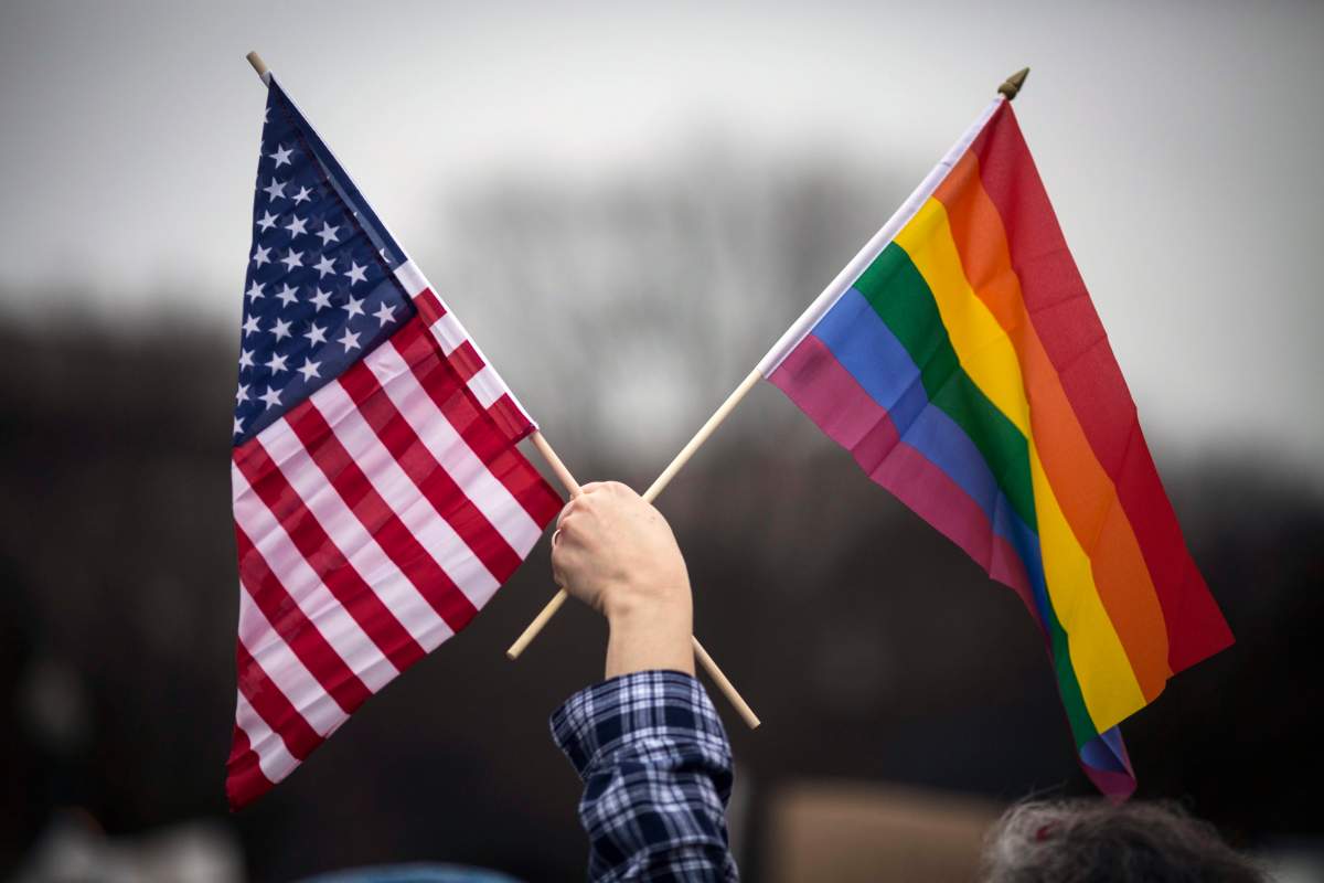 A participant holds both the U.S. national flag (L) and the LGBT community’s symbolic Rainbow flag (R) as people arrive on the mall for the Women’s March on Washington in Washington, D.C. on Jan. 21, 2017.