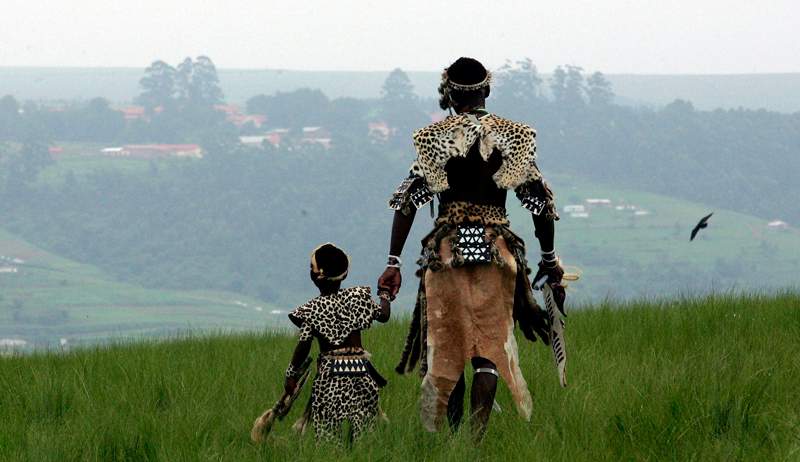 A man and his son, members of the Shembe Church, dressed in tribal leopard skins at the end of a pilgrimage on the holy Nlangakazi Mountain north of Durban, South Africa. 
