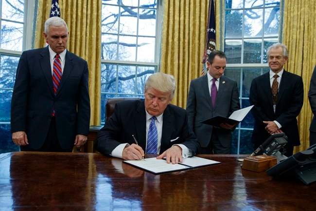 President Donald Trump signs an executive order to withdraw the U.S. from the 12-nation Trans-Pacific Partnership trade pact agreed to under the Obama administration, Monday, Jan. 23, 2017, in the Oval Office of the White House in Washington.