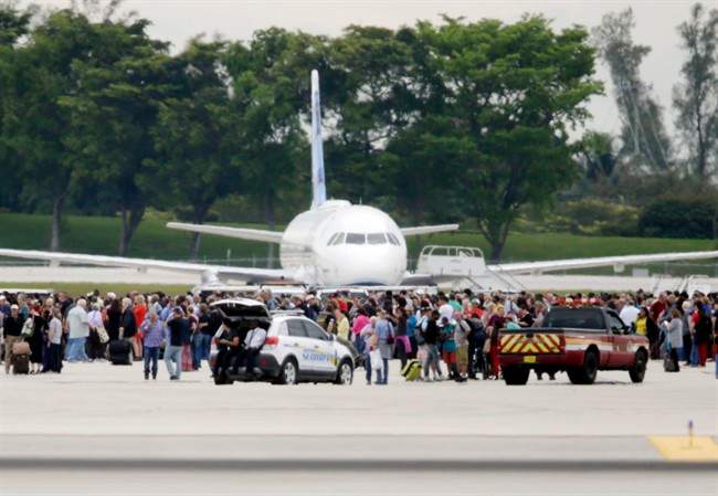 People stand on the tarmac at the Fort Lauderdale-Hollywood International Airport after a lone shooter opened fire inside the terminal, Friday, Jan. 6, 2017, in Fort Lauderdale, Fla.