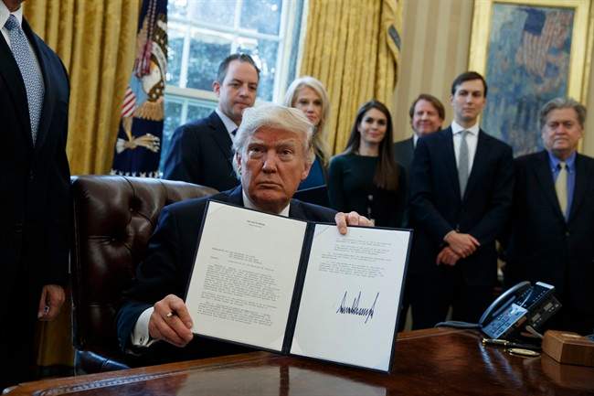 President Donald Trump shows his signature on an executive order on the Keystone XL pipeline, Tuesday, Jan. 24, 2017, in the Oval Office of the White House in Washington.