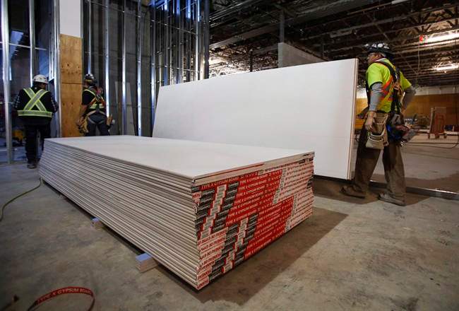 Construction workers move sheets of drywall at a building project in Calgary, Alta., Friday, Dec. 30, 2016. A decision expected later Wednesday could drive up the cost of rebuilding Fort McMurray after a wildfire swept through the northern Alberta city last spring.