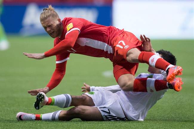 Canada's Marcel De Jong, top, is tackled by Mexico's Hirving Lozano during first half FIFA World Cup qualifying soccer action in Vancouver, B.C., on Friday, March 25, 2016.