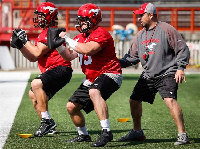Calgary Stampeders' Pierre Lavertu, centre, and Joe Circelli, left, take part in a drill during the first day of training camp in Calgary on June 1, 2014. Canadian offensive lineman Pierre Lavertu has re-signed with the Calgary Stampeders.The 26-year-old from Quebec City was going to be eligible for free agency in February. 