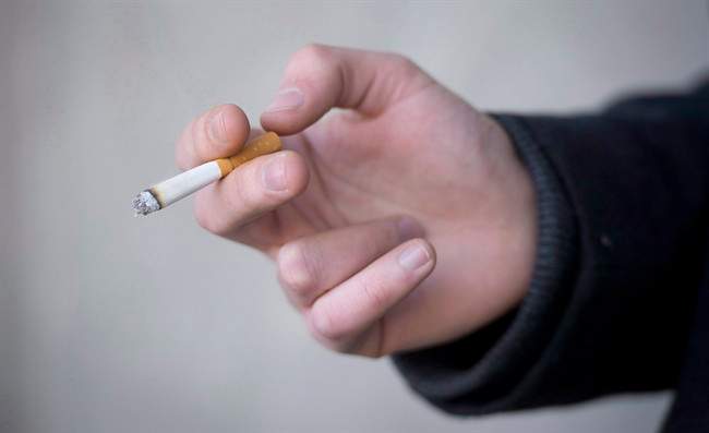 A smoker is seen holding his cigarette during a smoke break outside a building in North Vancouver, B.C. Monday, Jan. 20, 2014. 