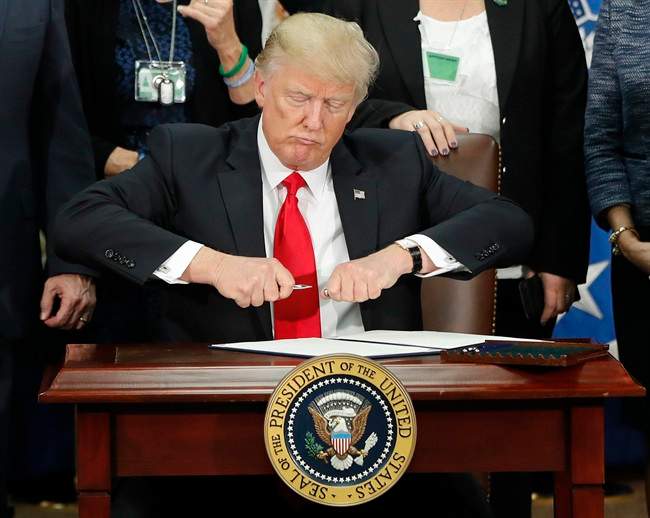 President Donald Trump takes the cap off a pen before signing executive order for immigration actions to build border wall during a visit to the Homeland Security Department in Washington, Wednesday, Jan. 25, 2017.