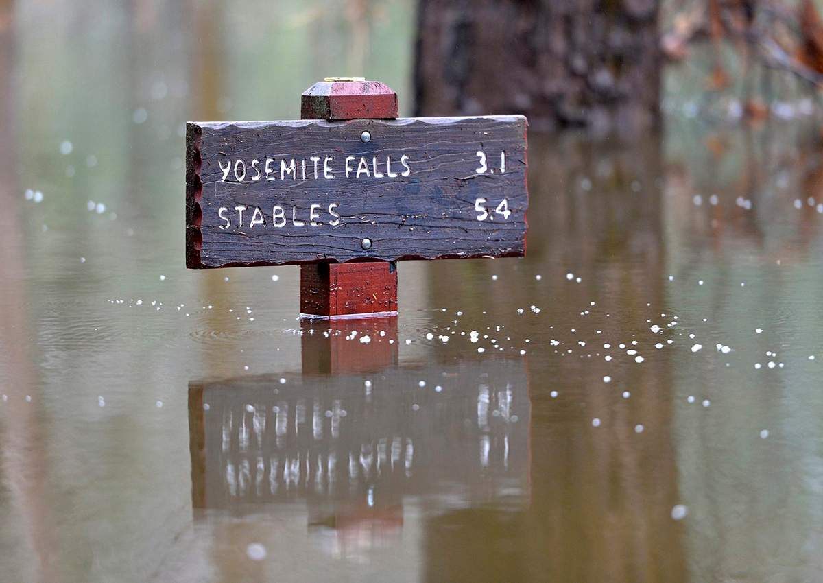 A sign is partially submerged in flood water at Yosemite National Park, Monday, Jan. 9, 2017.