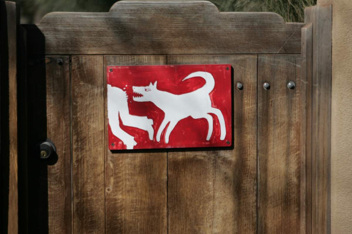 A sign posted on the garden door of an upscale Canyon Road home on the east side of Santa Fe warns would-be trespassers to beware of the dog.