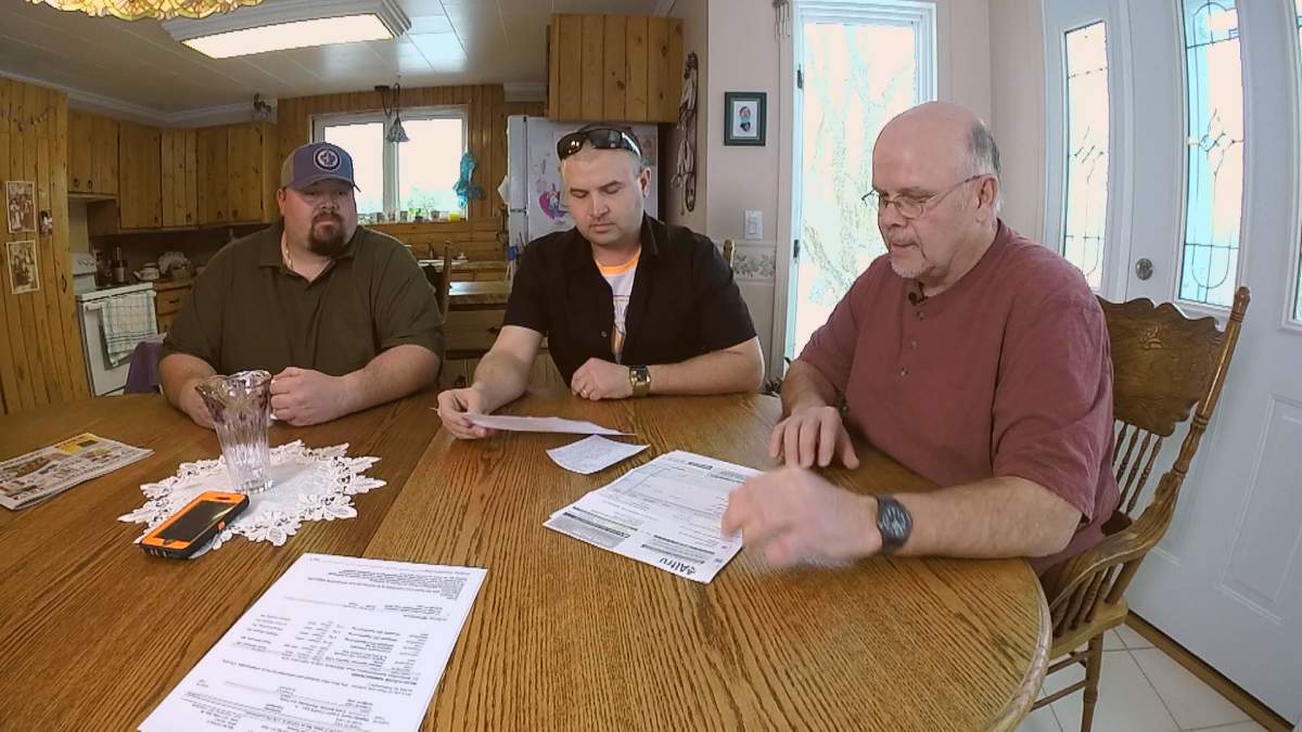 Robin Milne looks over paper work and how much he is being forced to pay at his home in Sprague, Manitoba. 