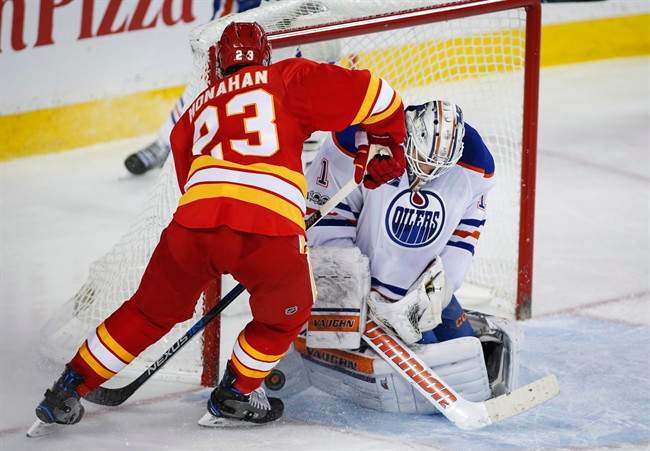 Edmonton Oilers' goalie Laurent Brossoit, right, stops Calgary Flames' Sean Monahan during third period NHL hockey action in Calgary, Saturday, Jan. 21, 2017.