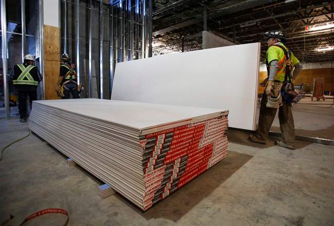 Construction workers move sheets of drywall at a building project in Calgary, Alta., Friday, Dec. 30, 2016. Anti-dumping duties on U.S. drywall imports into Western Canada have hiked prices for the building product but have also resulted in new manufacturing jobs, says the company whose complaint prompted the trade tariffs. CertainTeed Gypsum Canada has added about 30 employees since duties began in September at its drywall plants in Vancouver, Calgary and Winnipeg to boost production, said spokesman Mike Loughery in an email. 