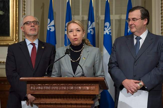 In this 2017 file photo, Quebec Labour Minister Dominique Vien flanked by Quebec Finance Minister Carlos Leitao, left, and Quebec Employment and Social Solidarity Minister Francois Blais announces an increase in the minimum wage, at the legislature in Quebec City. Vien announced the minimum wage would increase next may to $12 an hour. Wednesday, Jan. 17, 2018.