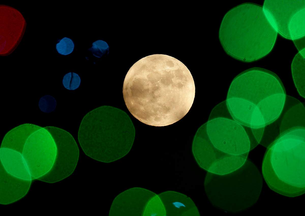  In this Thursday, Dec. 24, 2015, file photo, a nearly-full moon is seen among Christmas lights at a holiday display near Lenexa, Kan. 