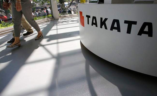 In this May 4, 2016 file photo, visitors walk by a Takata Corp. desk at an automaker's showroom in Tokyo.