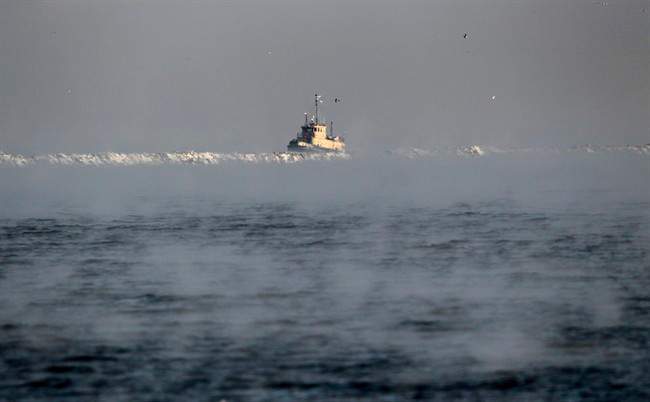 A search vessel travels amidst the morning fog near a break wall at Lake Erie to help in the recovery operation of a missing plane, Jan 6, 2017.