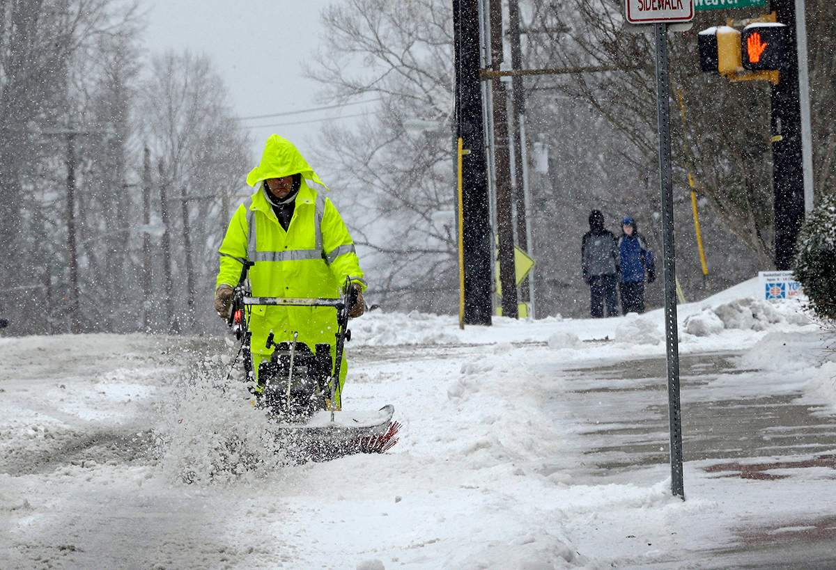 A city worker removes snow from a crosswalk as a winter storm blankets the area in Carrboro, N.C., Saturday, Jan. 7, 2017. (AP Photo/Gerry Broome)