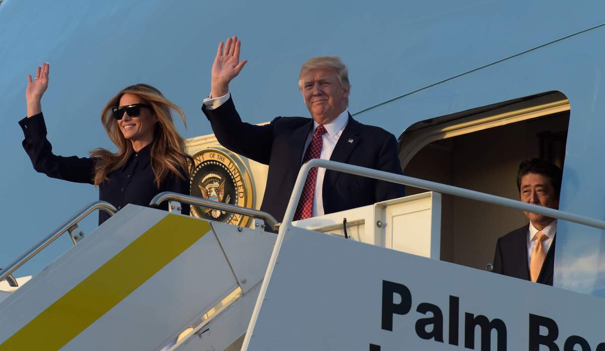 President Donald Trump, center, and first lady Melania Trump, left, wave from the top of the steps of Air Force One at Palm Beach International Airport in West Palm Beach, Fla., Friday, Feb. 10, 2017, as Japanese Prime Minister Shinzo Abe, right, waits to exit the plane.