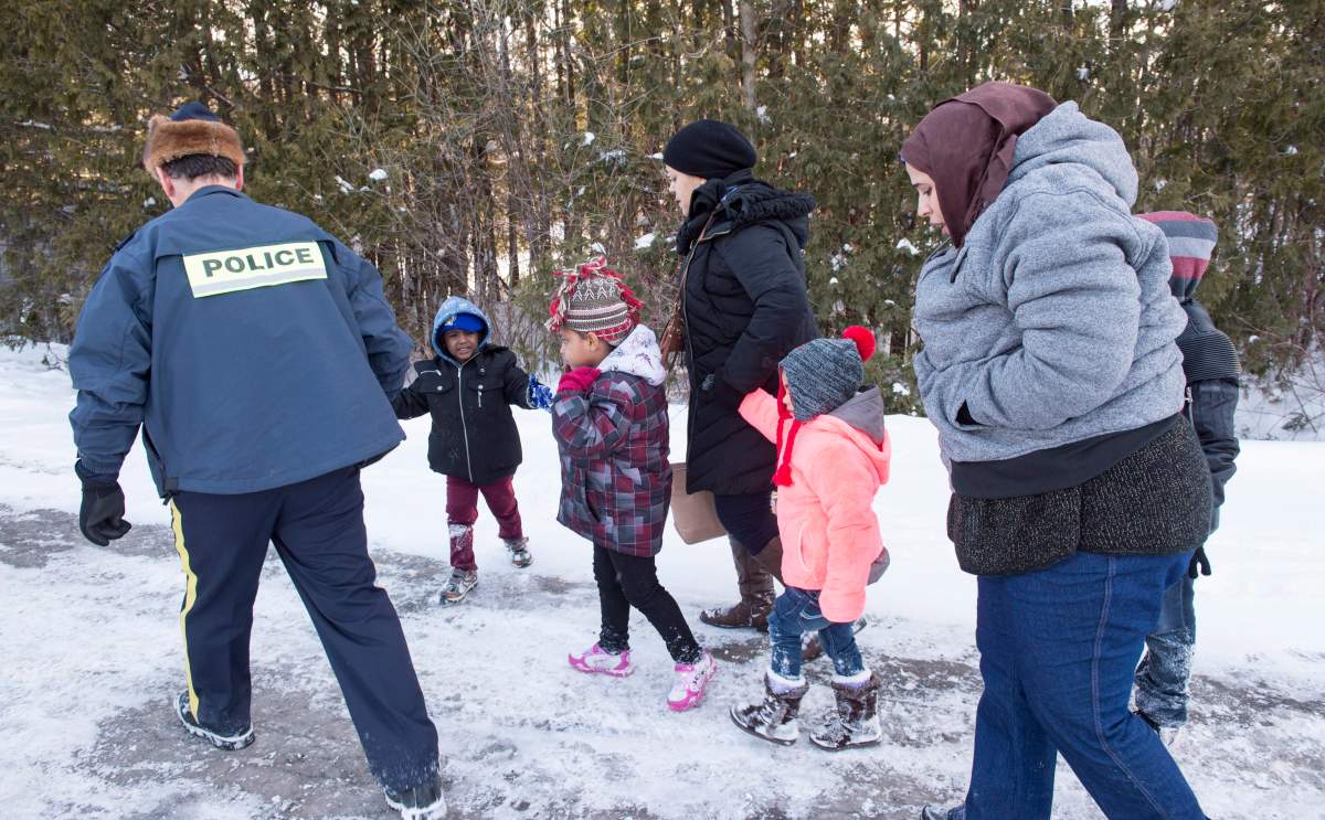 Family members from Somalia are escorted by RCMP officers after crossing the U.S.-Canada border near Hemmingford, Que., on Feb. 17.
