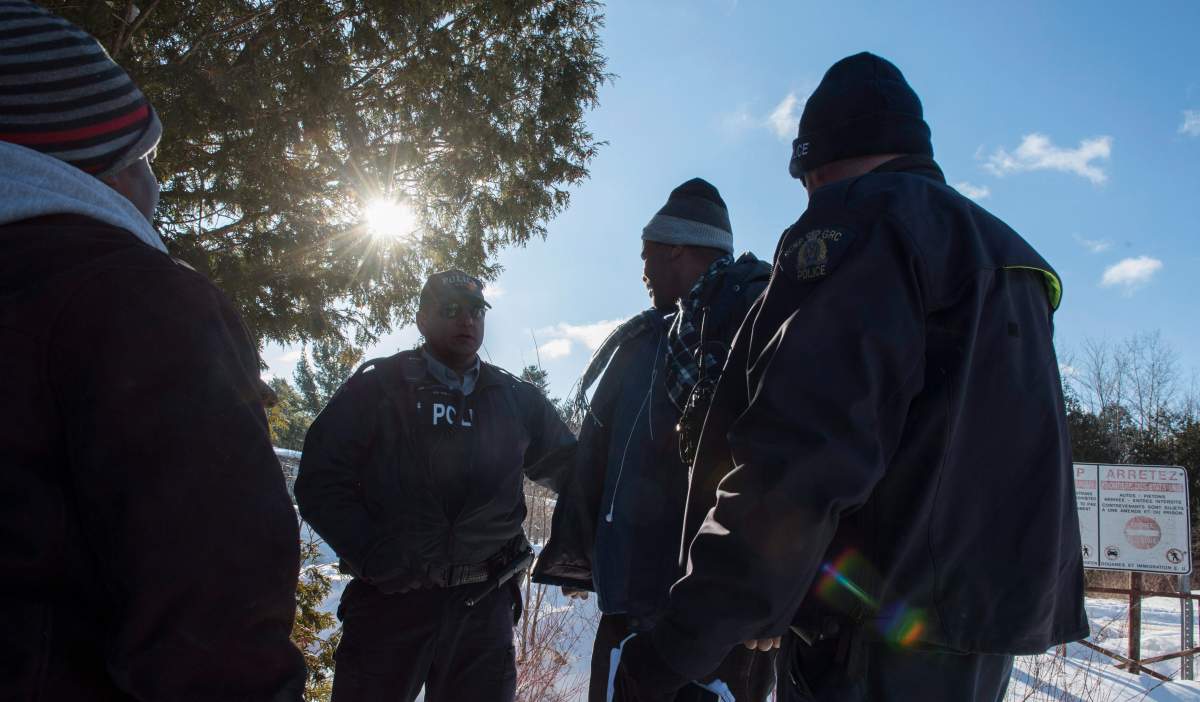 RCMP officers arrest two Somali men after crossing the U.S.-Canada border with their families into Canada near Hemmingford, Que., on Friday, Feb. 17, 2017. A number of refugee claimants are braving the elements to illicitly enter Canada.