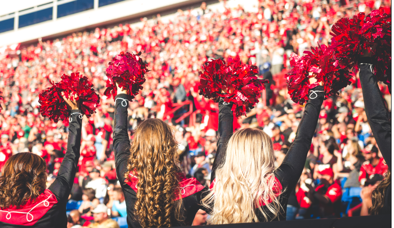 Members of the Calgary Stampeders Outriders cheer in front of a packed stadium.