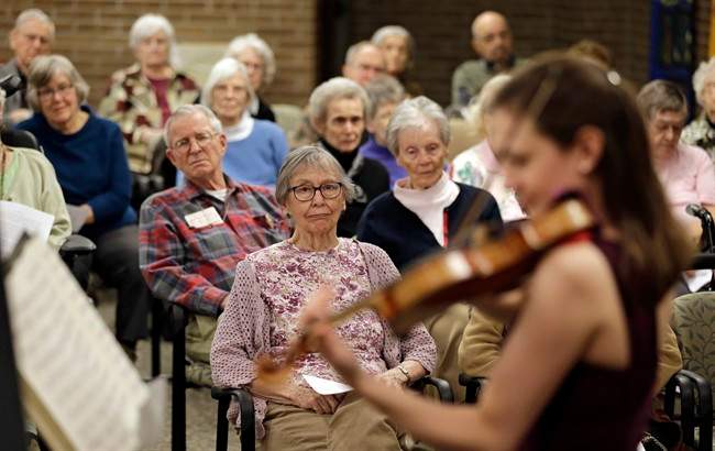 In this Thursday, Feb. 16, 2017 photo, residents watch Nina Sandberg play violin at Judson Park, in Cleveland Heights, Ohio. 