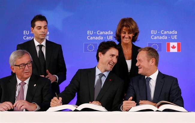 Canadian Prime Minister Justin Trudeau, center front, sits with European Commission President Jean-Claude Juncker, left, and European Council President Donald Tusk, right, as they sign the Comprehensive Economic and Trade Agreement (CETA) during an EU-Canada summit at the European Council building, in Brussels in an October 30, 2016, file photo.