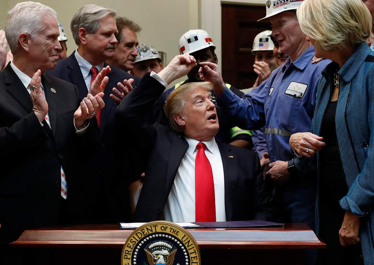President Donald Trump hands the pen he used to sign H.J. Res. 38 to Kevin Hughes, General Manager, Murray Energy Corporation, second from right, in the Roosevelt Room of the White House in Washington, Thursday, Feb. 16, 2017. 