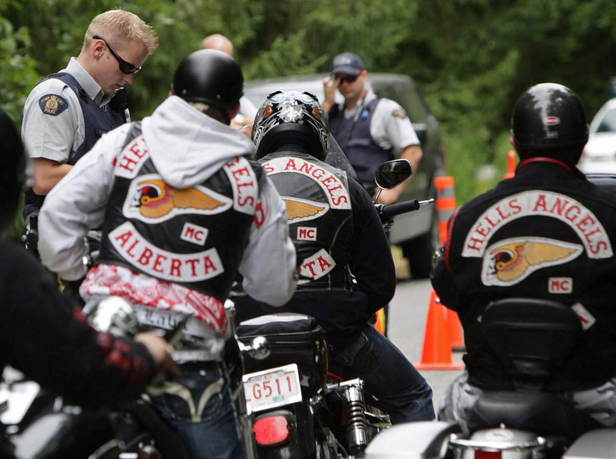 FILE – An RCMP officer stops Alberta members of the Hell’s Angels motorcycle gang at a roadblock after they left the White Rock chapter’s property in Langley, B.C., on July 26, 2008.