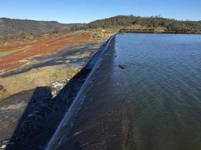 In this Feb. 11, 2017, photo released by the California Department of Water Resources, water flows over an emergency spillway at the Oroville Dam at Lake Oroville in Oroville, Calif.