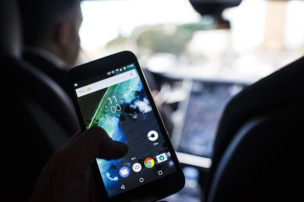 The Uber Technologies Inc. ride-hailing service app sits on a smartphone screen in the rear of an Uber Technologies Tesla Motors Inc. Model S electric automobile, in Madrid, Spain, on Friday, Jan. 13, 2017. Ride-hailing service Uber Technologies has launched its first electric car taxi service in Madrid, operating a fleet of Tesla Model S electric vehicles. Photographer: Angel Navarrete/Bloomberg via Getty Images.