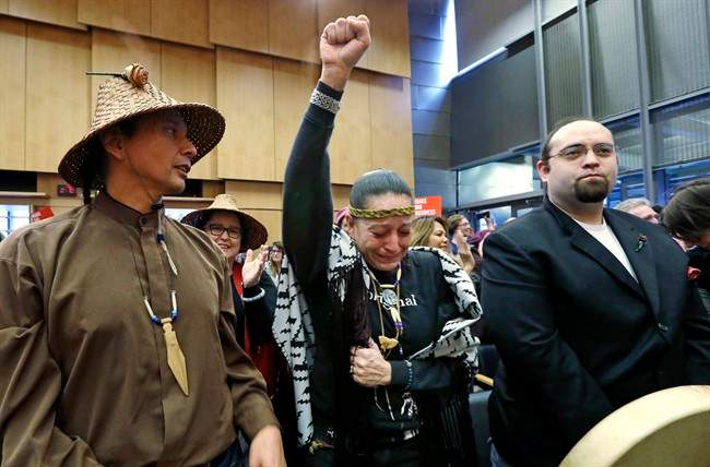 Olivia One Feather, center, of the Standing Rock Sioux tribe, holds her fist up and cries tears of happiness after the Seattle City Council voted to divest from Wells Fargo over its role as a lender to the Dakota Access pipeline project and other business practices, Tuesday, Feb. 7, 2017, in Seattle. Wells Fargo manages more than $3 billion of Seattle's operating account. (AP Photo/Elaine Thompson).